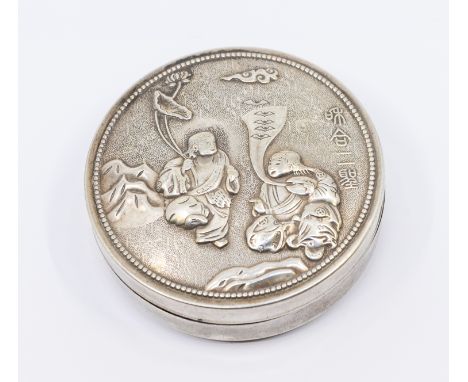 A Chinese white metal circular snuff box and cover, the cover embossed with two seated Deities within landscape, character ma
