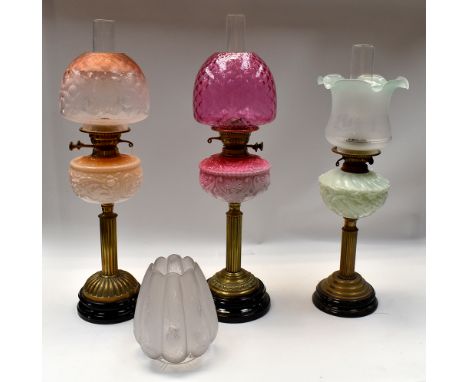 A small collection of late 19th/early 20th century oil lamps, all with moulded pink, light green and cream/orange centres, al
