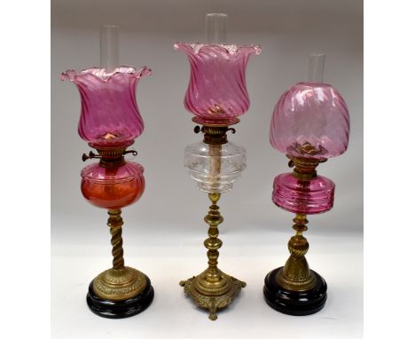 A small collection of three late 19th/early 20th century oil lamps, various designs to include; two ruby glass centred with b