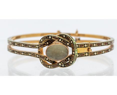 A 19th century champlevé enamel and gold mourning bangle, comprising a central knot inset with a hinged glazed compartment (o