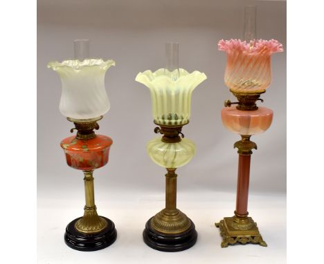 A small collection of three late 19th/early 20th century oil lamps, various designs to include; a stylish mixed coloured glas