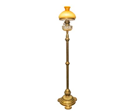 A late 19th century tall columned standing oil lamp, circular footed base with three curved feet, with flume and light orange