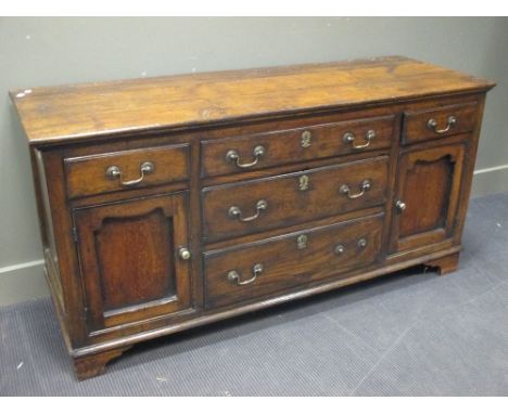 An 18th century oak dresser base, with drawers and cupboards, brass handles and on bracket feet 78 x 158 x 55cm  