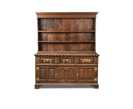 An 18th century oak dresser, with a boarded plate rack and dentil moulded cornice, above a base fitted with three drawers and