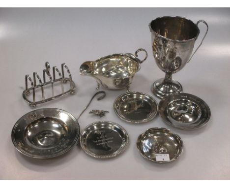 A silver two handled cup, a silver sauce boat, a silver toast rack, a silver armada dish with horse motif and another silver 