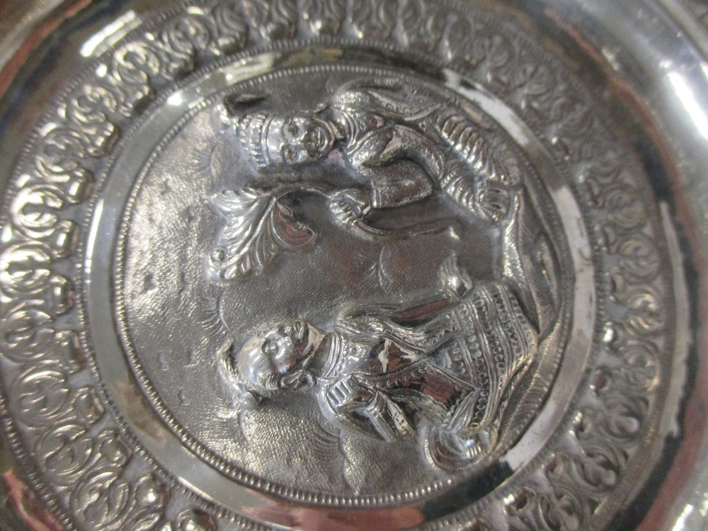 An Asian silver embossed dish and a small decorated dish in Cheffins