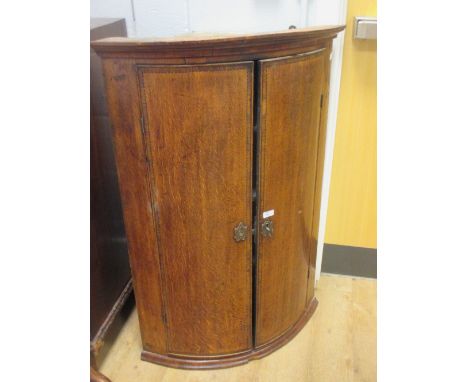 A George III oak bow front corner cupboard  