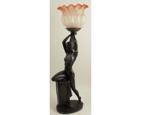 An Art Deco style plaster lamp base, formed as a naked female with her knee on a pedestal, finished in black, with frilled et