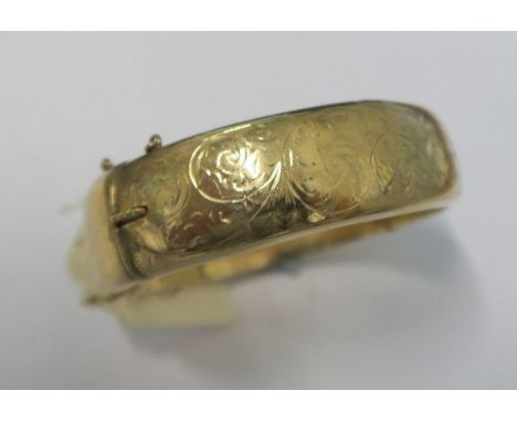 A 9 carat gold half engraved hinged bangle, Chester 1960, approximately 18mm wide, 24.9g gross