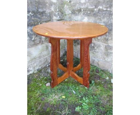 An Arts &amp; Crafts oak Hispanic style circular lamp table, in the style of Sir Peter Lorimer, with shaped plank style legs 