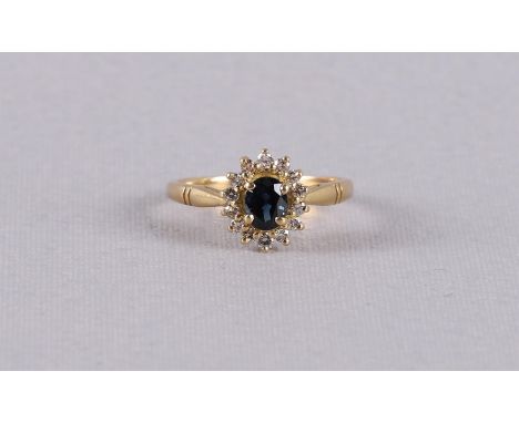 An 18 carat 750/1000 gold ring with an oval faceted blue sapphire and an entourage of 14 brilliants. Ring size 15.5 mm.