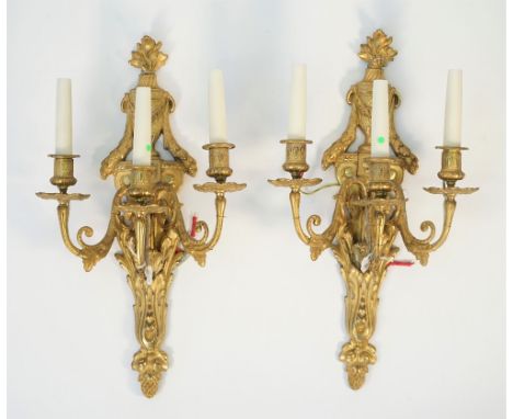 A pair of Empire style ormolu three light wall appliques, 20th century, each with flaming urn finials and acanthus cast backp