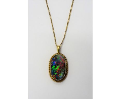 A gold mounted oval opal single stone pendant, decorated with a ropetwist border, with a 9ct gold neckchain, on a boltring cl