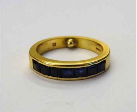 An 18ct gold and sapphire half hoop ring, channel set with a row of seven square cut sapphires by Allan Christensen, Petworth