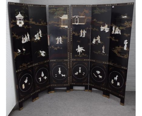 An early 20th century Chinese black lacquer six fold screen decorated in relief with mother-of-pearl figures, 240cm wide x 18