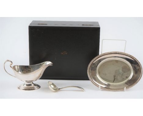 A Mappin &amp; Webb silver sauceboat, with a sauce ladle and an oval stand, decorated with gadrooned rims, combined weight 35