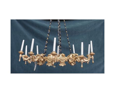 An Italian giltwood ten light corona chandelier, the foliate carved corona issuing ten swan neck branches, suspended by four 