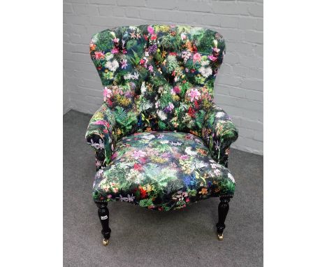 A Victorian style button back armchair, with floral pattern upholstery, on turned ebonised supports, 75cm wide x 105cm high.