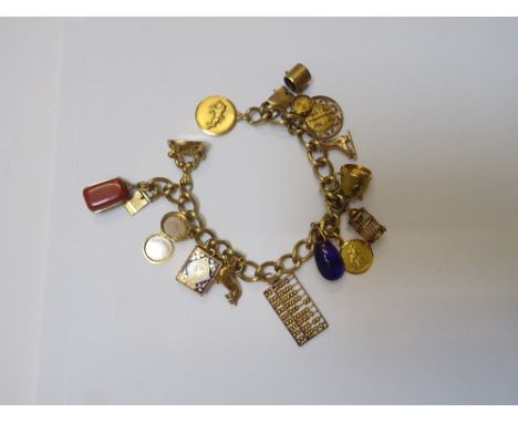 A gold decorated curb link charm bracelet, on a snap clasp, detailed 14 K, fitted with fourteen various gold and other charms