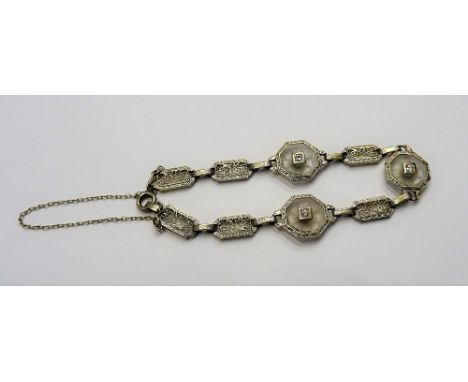 A two colour gold and diamond bracelet, formed as a row of filigree pierced panel shaped links and with three octagonal diamo