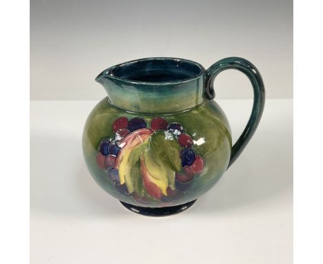 A stunning Moorcroft pottery pitcher featuring a vibrant hand-painted fruit motif with rich hues of green, red, and yellow on