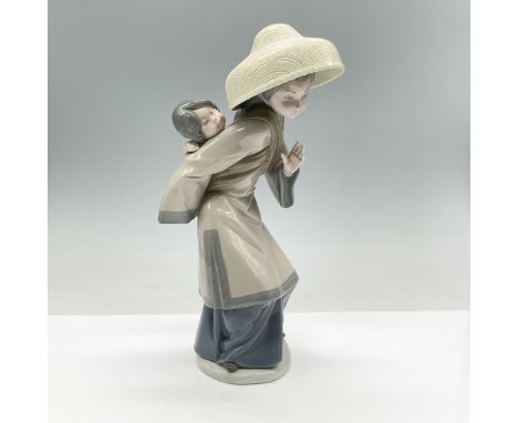 Exquisitely hand-crafted in Spain, portrays a serene woman gently cradling her baby in a traditional wrap. This delicate porc