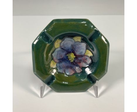 A elegant Moorcroft ashtray featuring a hand painted clematis flower in soft purple and yellow hues, set against a rich green