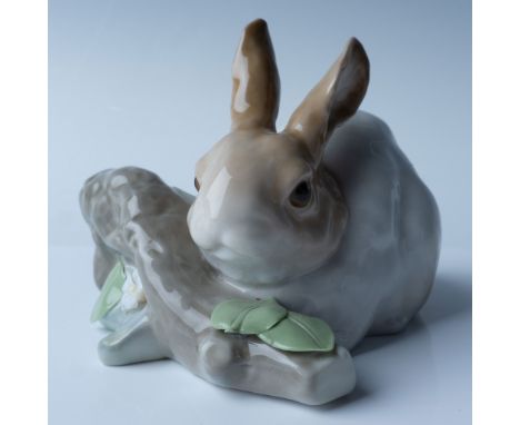 This Lladro porcelain figurine, titled Rabbit Eating (Brown), depicts a detailed rabbit nibbling on foliage, with a soft pale