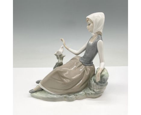 This Lladro porcelain figurine depicts a serene woman seated on a rock base, gently interacting with a bird perched nearby. C