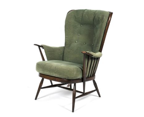 An Ercol dark stained buttoned back upholstered armchair. With high spindle back, with drop-in green cushions, on tapering sp