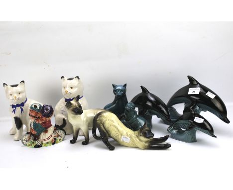 An assortment of ceramics. Including three Poole dolphins, a Beswick cat, a pair of cats etc