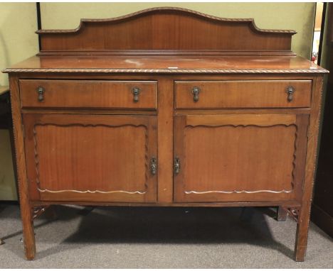 A 20th century mahogany sideboard. Two short drawers over a pair of doors opening to reveal a shelf, carved and pierced detai