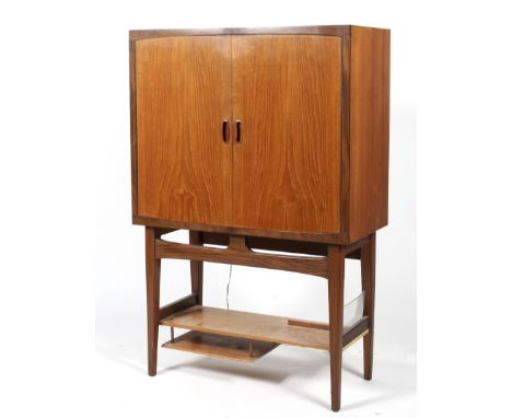 A mid-century teak drinks cabinet. The double doors with recessed handles, the mirrored interior fitted with glass compartmen