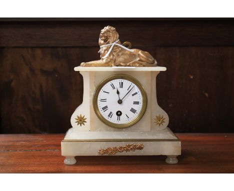 A Victorian alabaster mantel clock. Adorned with a gilt metal finial in the form of a Lion, the enamel dial with Roman numera