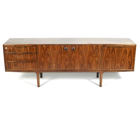 A 1970s AH McIntosh rosewood sideboard. With a pair of central cupboard doors enclosing a shelf, flanked by a bank of three d