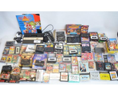 An Atari 2600 vintage gaming console (no controllers) and a collection of vintage video games, mostly tapes for Commodore 64/
