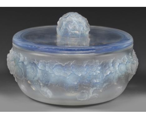 Bläulich opalisierendes Glas. Niedrige, gebauchte Form mit flachem Deckel, blütenreliefierte Wandung, kugelig gewölbter Knauf
