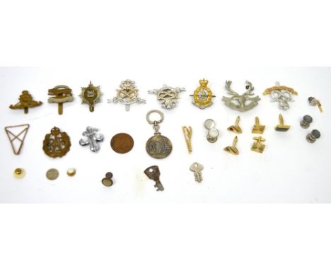 A collection of 20th century worldwide military cap badges, various cufflinks, tie pins and studs.