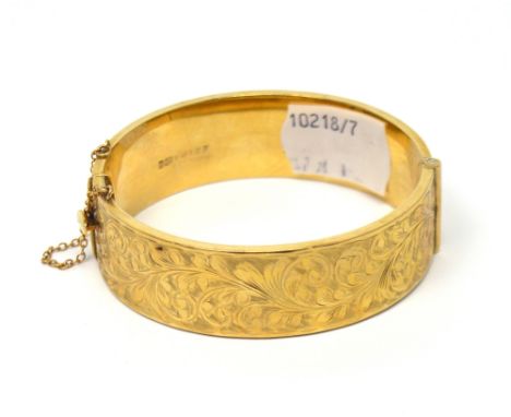 A 9ct yellow gold engraved snap bangle with safety chain, approx 25.2g.