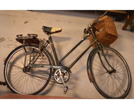 A vintage green Ray bicycle with wicker carrying basket to front.