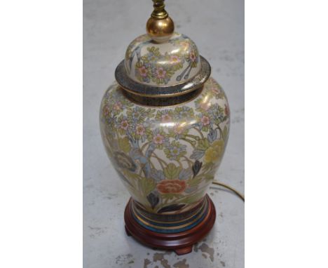 A 20th century Oriental table lamp decorated with peonies and cherry blossom, gilt-heightened, raised on a wooden base with c