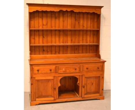 A large pine dresser, carved pediment and boarded plate rack above numerous drawers to bracket feet, width 164cm.   CONDITION
