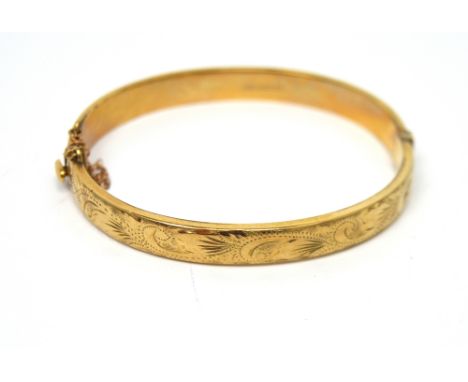 A 9ct yellow gold engraved snap bangle with safety chain, 10.7g.