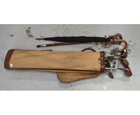A quantity of golf clubs contained within a golf bag, an umbrella and a shooting stick.