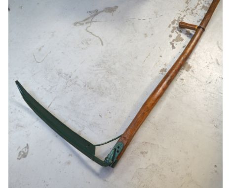 A vintage scythe with green-painted blade.