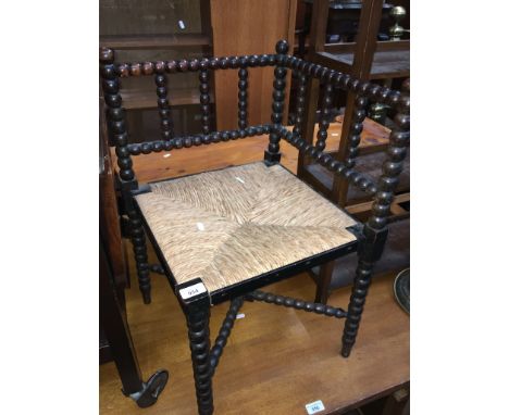 An Arts and Crafts ebonised and bobbin turned corner chair, height 62cm, width 41.5cm and depth 41.5cm.  