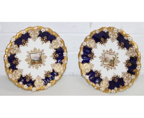 A pair of 19th century Coalport porcelain plates, blue and gilt ground with hand painted landscape vignettes to the centre, e