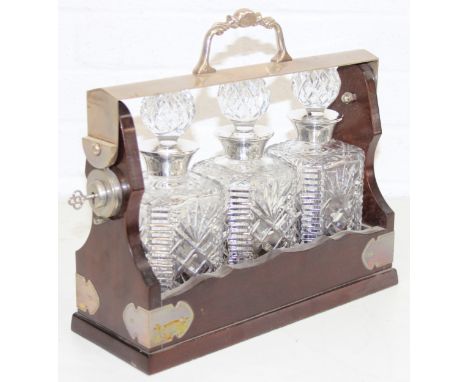 A three decanter wooden tantalus with three hallmarked silver-collared decanters. with key, 35cm W x 32cm H
