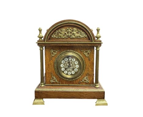 French - Early 20th century oak cased 8-day striking mantle clock, with an arched top, finials and applied brass casting depi