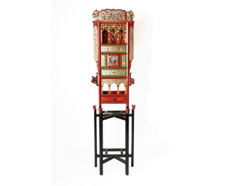 A CARVED PARCEL GILT AND RED WASH STAND
The cresting carved and pierced with warrior figures and birds, above a painted panel